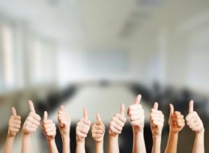 Pupils thumbs ups in the foreground with a classroom in the background