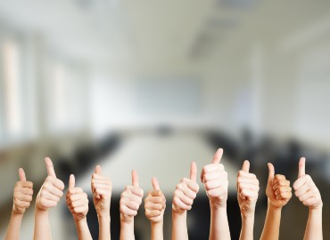 Pupils thumbs ups in the foreground with a classroom in the background