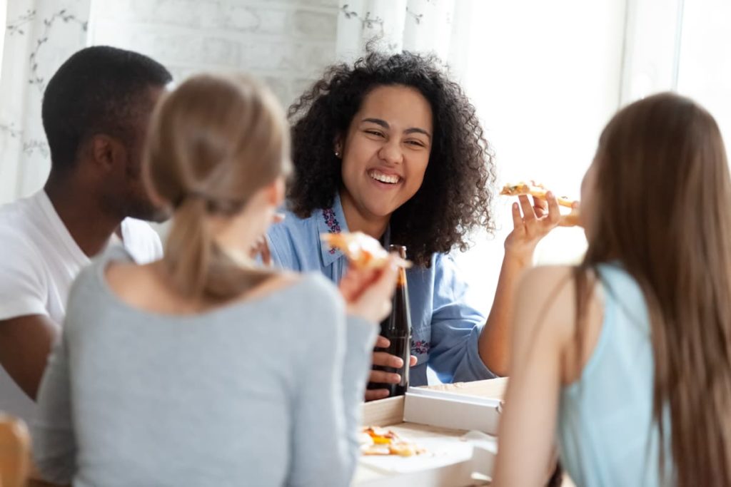 A photograph of young adults eating pizza