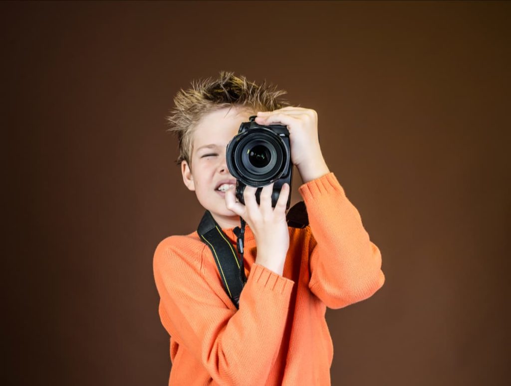 A young man is holding a professional camera and taking a photo