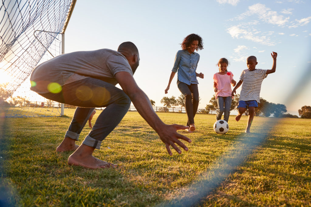 A family playing football kicking the ball towards the goal