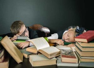 two children sleeping on a pile of books