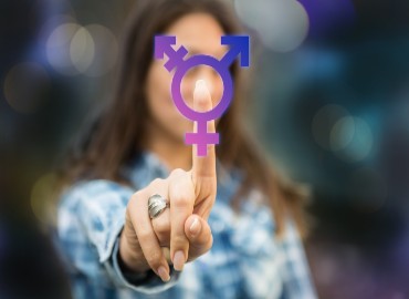LGBTQ symbol in the foreground being held up by a blurred woman in the background