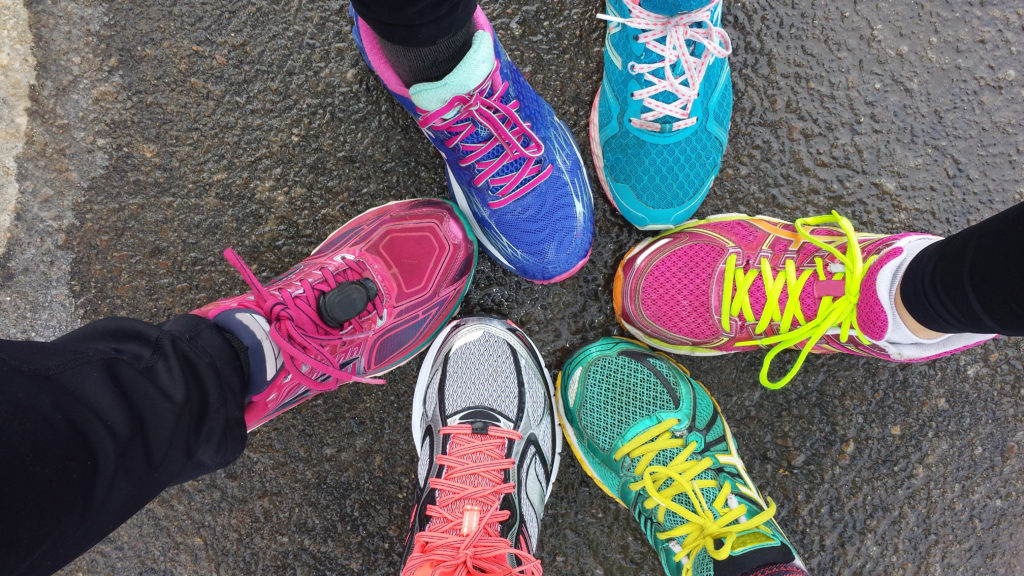 bird's eye view of six people's feet in bright coloured trainers