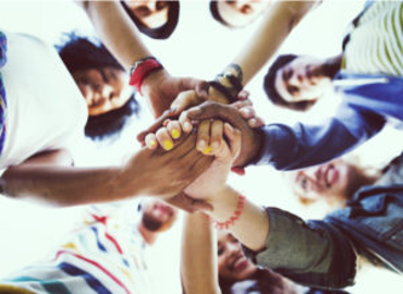 Group of young people putting hands together in the middle of a circle