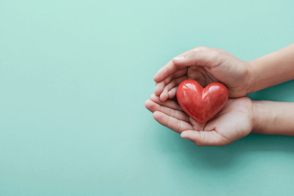 Photo of two hands holding a wooden heart