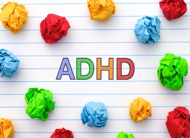 Letters ADHD surrounded by screwed up coloured bits of paper