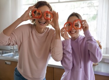 happy woman and girl holding pepper circles over their eyes